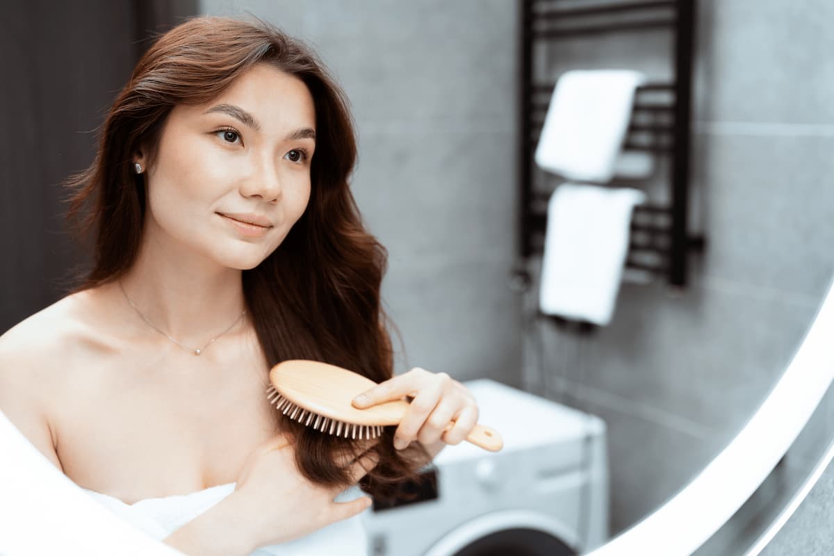 young woman brushing hair in modern bathroom mirro 2024 05 16 15 34 02 utc 1